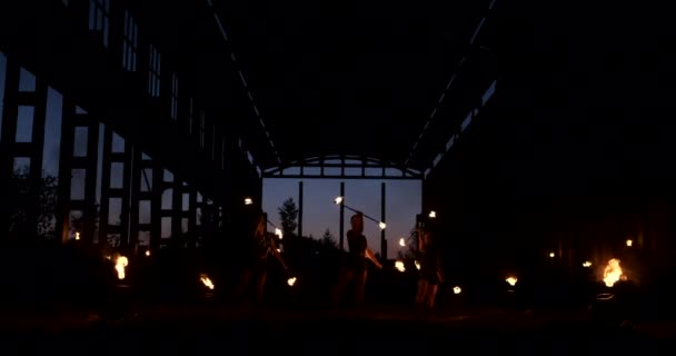 Un groupe de personnes avec du feu et des torches dansant au coucher du soleil dans le hangar au ralenti. Spectacle incendie — Video