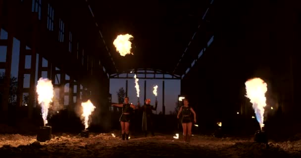 Yavaş çekim: Hangarda ateş gösterisi üç kadın sanatçı ve alev makinesi olan bir adam gösteriyor. — Stok video