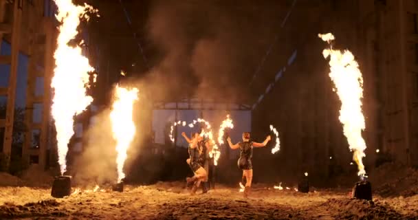 Un grupo de personas con fuego y antorchas bailando al atardecer en el hangar en cámara lenta. espectáculo de fuego — Vídeo de stock