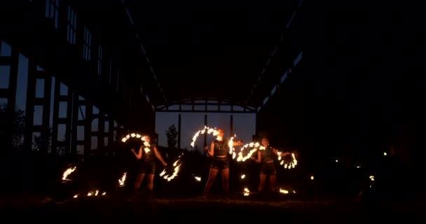 Повільний рух: Пожежне шоу в ангарі показує трьох художниць і чоловіка з вогнеметами . — стокове відео