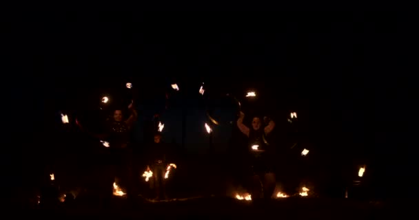 Drei Frauen mit brennenden Reifen tanzen mit feurigen Fackeln in Lederkleidung in einem dunklen Hangar und demonstrieren eine Zirkusfeuershow in Zeitlupe. — Stockvideo