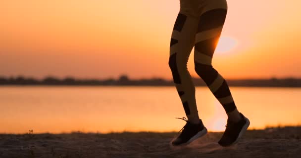 Fitness kobieta rozciąganie robi lonży rozciągać ćwiczenia. Zawodniczki szkolenia sportowiec rozciąga się na zewnątrz w pięknej przyrody w Silhouette podczas plaży zachód słońca. — Wideo stockowe
