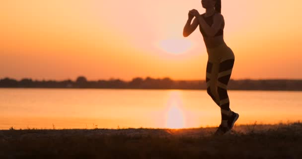 Frau macht Ausfallschritte, duckt sich im Freien und trainiert ihren Körper. junge schlanke Frau trainiert Muskeln an Beinen, Hüften und Gesäß — Stockvideo