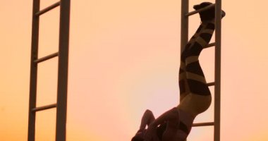 Karın kasları egzersizleri. Genç bir güzellik atletik gün batımında göle karşı yaz kadın spor barda yavaş hareket abs için egzersizler yapıyor.