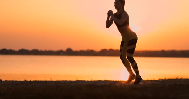 Fitness kvinna stretching gör utfall stretch motion. Kvinnlig idrottare utbildning utfall sträcker sig utanför i vacker natur i silhuett under stranden solnedgång. — Stockvideo
