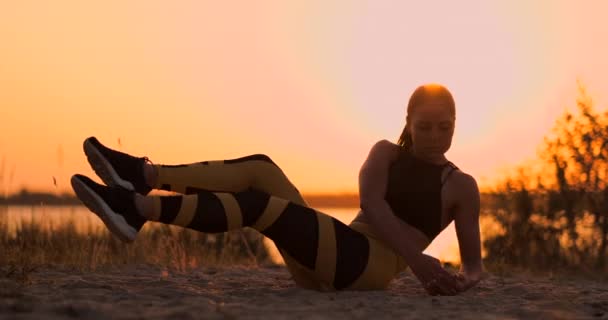 Η γυναίκα της γυμναστικής κάνει κοιλιακούς στην παραλία. Γυμναστήριο γυναίκα κάνει κοιλιακούς γυμναστική άσκηση προς την παραλία. Θηλυκιά εφαρμογή αθλητής εκπαίδευση κοιλιακό μεσοτμήμα. — Αρχείο Βίντεο