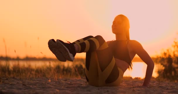 Mujer de fitness haciendo crujidos en la playa. Mujer de fitness haciendo ejercicios de crujidos hacia la playa. Entrenamiento de atleta en forma femenina sección media abdominal . — Vídeos de Stock