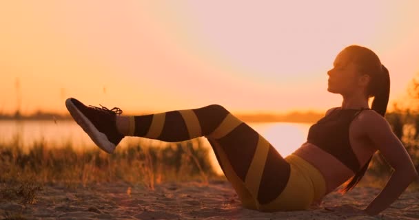 S'adapter femme en bonne santé étirement sur tapis de yoga sur la plage en bord de mer, faire des exercices abdominaux croque, l'entraînement et le mode de vie. Entraînement assis sur la plage du quai au coucher du soleil . — Video