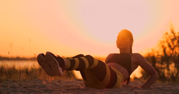 Fit friska kvinna stretching på yogamattan på stranden havet, gör övning buk crunches, utbildning och livsstil. Sit ups Training på dock Beach i solnedgången. — Stockvideo