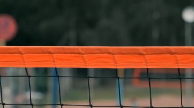 Yavaş Hareket, Yakın Çekim, Düşük Açı: Ağda voleybol oynayan tanınmayan genç kadın elleri. Hücum oyuncusu topu çiviler ve rakip bir turnuva sırasında topu sağ üstten engeller.