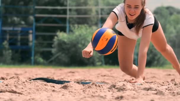 Mladá sportovkyně se potopit do písku a během utkání na plážový volejbal si šetří bod. Veselá Kavkazská dívka skáče a hroutí se do bílého písku při plážové turnaji