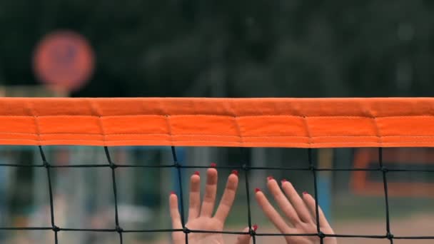 Slow motion, närbild, låg vinkel: oigenkännlig unga kvinnliga händer spela volleyboll på nätet. Offensiv spelare spikar bollen och motståndaren blockerar det precis ovanför nätet under en turnering. — Stockvideo