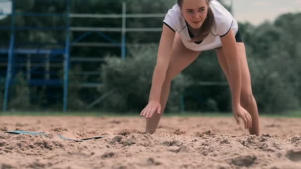 Slow motion: en ung kvinna hoppar i höst träffar bollen på sanden. Volleybollspelare gör ett lag och spelar bollen av på hösten — Stockvideo