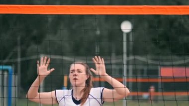 Profesyonel voleybol plaj turnuvasında kadın hizmet vermektedir. Voleybol net oyuncu uygularken görünümü engeller