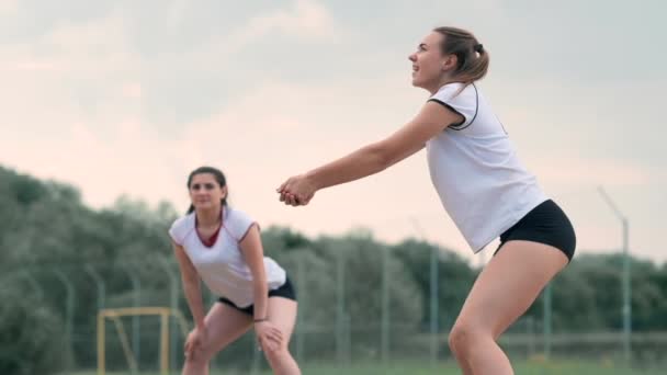 Mujer joven jugando voleibol en la playa en un equipo llevando a cabo un ataque golpeando la pelota. Chica en cámara lenta golpea la pelota y llevar a cabo un ataque a través de la red — Vídeos de Stock