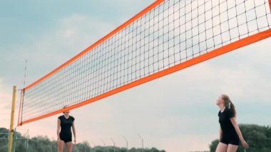 Profesyonel Plaj Voleybolu Turnuvasında Yarışan Kadınlar. Bir defans oyuncusu 2 kadın uluslararası profesyonel plaj voleybolu sırasında bir atış durdurmak için çalışır