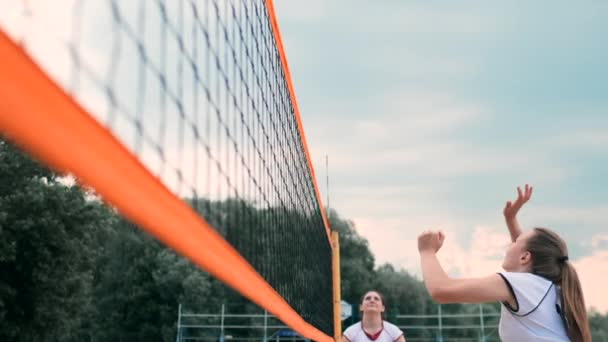 Mulheres competindo em um torneio profissional de vôlei de praia. Um defensor tenta parar um tiro durante o vôlei de praia profissional internacional de 2 mulheres — Vídeo de Stock