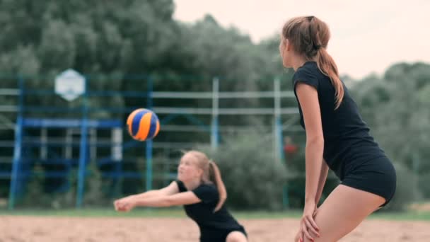 年轻女子在沙滩上打排球，在一队进行攻击击球。女孩在慢动作击球，并通过网进行攻击 — 图库视频影像
