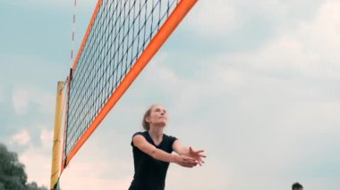 Profesyonel Plaj Voleybolu Turnuvasında Yarışan Kadınlar. Bir defans oyuncusu 2 kadın uluslararası profesyonel plaj voleybolu sırasında bir atış durdurmak için çalışır