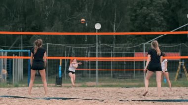 Plajda voleybol oynayan genç kadın atak gerçekleştiren bir takım topa vurdu. Yavaş çekimde kız topa vurur ve net üzerinden bir saldırı yürütmek