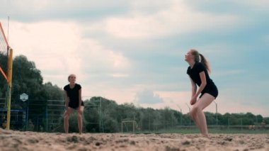 Profesyonel Plaj Voleybolu Turnuvasında Yarışan Kadınlar. Bir defans oyuncusu 2 kadın uluslararası profesyonel plaj voleybolu sırasında bir atış durdurmak için çalışır
