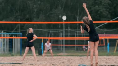 Kadın voleybol servisi. Plajda yavaş çekimde dururken voleybola hizmet etmeye hazırlanıyor kadın.