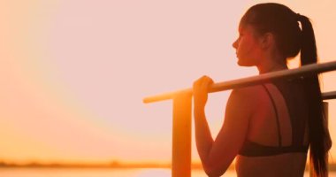 Tema kadın spor ve sağlık. Kıvırcık uzun saçlı, açık hava spor sahasında poz veren güzel beyaz kadın. Tema kadın spor ve sağlık.