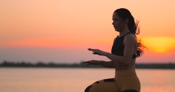 Kadın, gün batımında göletin yakınındaki sahilde koşarken trenler. Şafakta eğitim. — Stok video