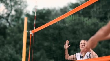 Profesyonel Plaj Voleybolu Turnuvasında Yarışan Kadınlar. Bir defans oyuncusu 2 kadın uluslararası profesyonel plaj voleybolu sırasında bir atış durdurmak için çalışır