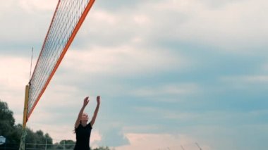 Profesyonel Plaj Voleybolu Turnuvasında Yarışan Kadınlar. Bir defans oyuncusu 2 kadın uluslararası profesyonel plaj voleybolu sırasında bir atış durdurmak için çalışır