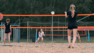 Kadın voleybol servisi. Plajda yavaş çekimde dururken voleybola hizmet etmeye hazırlanıyor kadın.