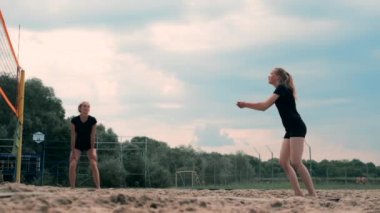 Plajda voleybol oynayan genç kadın atak gerçekleştiren bir takım topa vurdu. Yavaş çekimde kız topa vurur ve net üzerinden bir saldırı yürütmek