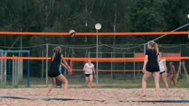Plajda voleybol oynayan genç kadın atak gerçekleştiren bir takım topa vurdu. Yavaş çekimde kız topa vurur ve net üzerinden bir saldırı yürütmek