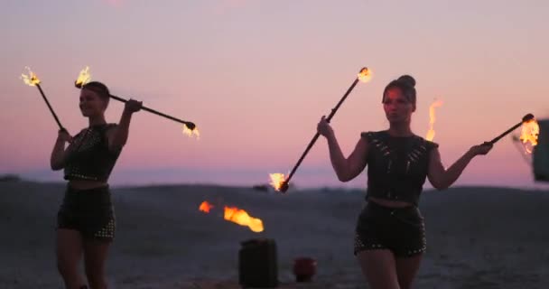 Kvinnor med eld i solnedgången på sanden dans och Visa tricks mot den vackra himlen i slow motion. — Stockvideo