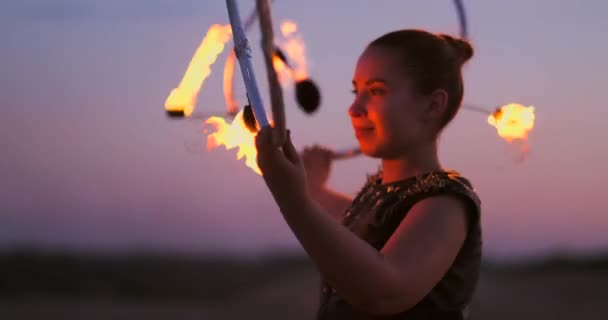 砂のダンスの日没時に火を持つ女性とスローモーションで美しい空に対してトリックを示す. — ストック動画