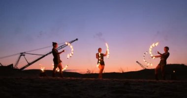 Profesyonel sanatçılar yavaş çekimde kum üzerinde bir yaz festivalinde bir ateş gösterisi göstermektedir. Sahilde gece yangın ile sirk çalışmadan dördüncü kişi akrobatlar.