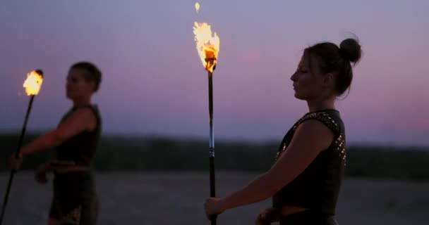 砂のダンスの日没時に火を持つ女性とスローモーションで美しい空に対してトリックを示す. — ストック動画