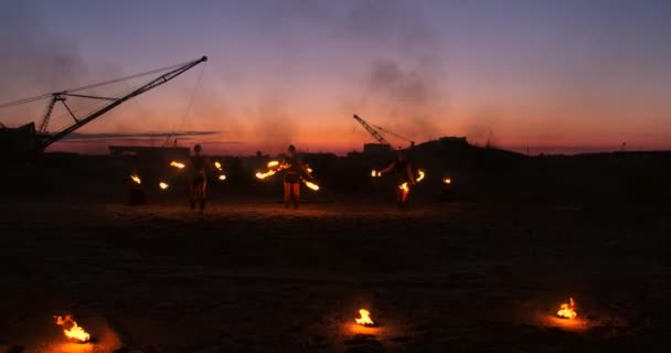 Fire show trzy kobiety w ich ręce skręcają płonących włóczni i fanów w piasku z mężczyzną z dwoma miotaczami ognia w zwolnionym tempie. — Wideo stockowe