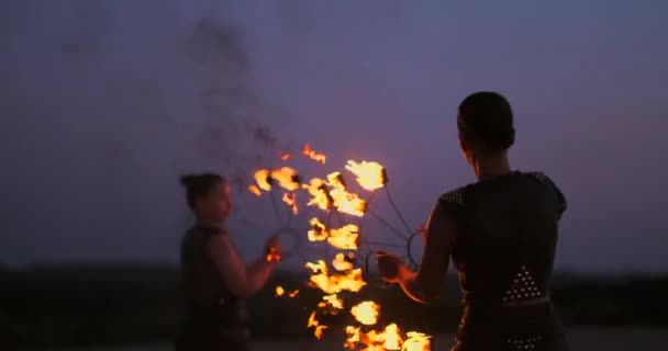 火を持つプロのサーカスのパフォーマーのグループは、火炎放射器を使用してスローモーションでダンスショーを示し、トーチを燃やすオブジェクトを回転させます. — ストック動画