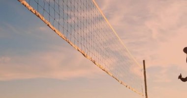 Yavaş Hareket, Düşük Açı, Close Up, Sun Flare: Plaj voleybolu oynayan atletik kız havada atlar ve güzel bir yaz akşamı net üzerinden topa vurur. Beyaz kadın bir puan