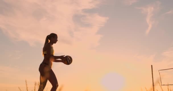 Αθλητικό κορίτσι παίζοντας Μπιτς βόλεϊ άλματα στον αέρα και χτυπά την μπάλα πάνω από το δίχτυ σε ένα όμορφο καλοκαιρινό βράδυ. Καυκάσια γυναίκα σκοράρει ένα σημείο — Αρχείο Βίντεο