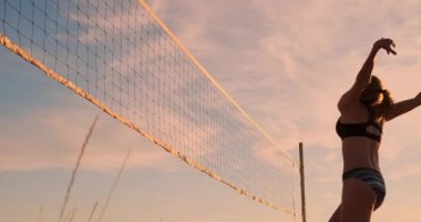 Seksi kız voleybolcular net yakın topu geçmek ve yavaş hareket gün batımında topa vurmak