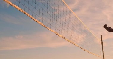 Genç kadın voleybolcular güneşli bir yaz akşamı pas ve net üzerinden topu başak. Fit Kafkas kızlar gün batımında plaj voleybolu oynuyor