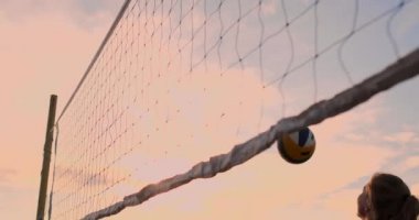 Seksi kız voleybolcular net yakın topu geçmek ve yavaş hareket gün batımında topa vurmak