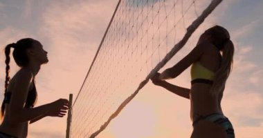 Seksi kız voleybolcular net yakın topu geçmek ve yavaş hareket gün batımında topa vurmak