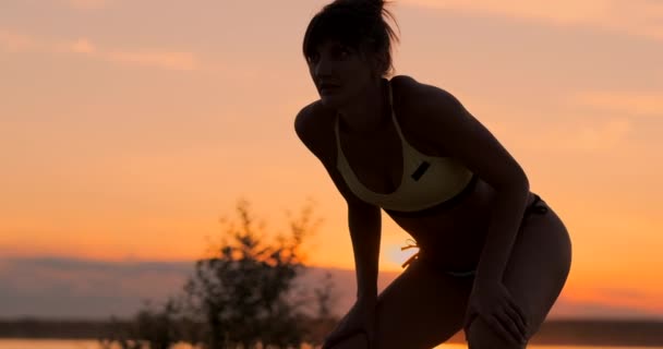 Ragazza di pallavolo di media distanza in bikini in attesa della palla in campo al tramonto dà il pass avambraccio durante una partita in spiaggia al rallentatore — Video Stock