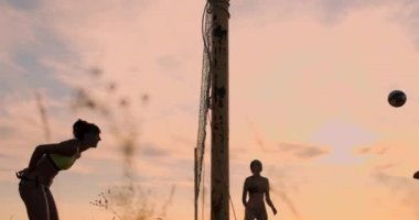 Yavaş çekimde gün batımında kumüzerinde yaz voleybolplajda bikini seksi voleybol kızlar oyun.