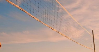 Plaj voleybolu maç kızlar kum üzerinde gün batımında yavaş çekimde topa vurdu.