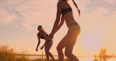Seksi kız voleybolcular net yakın topu geçmek ve yavaş hareket gün batımında topa vurmak
