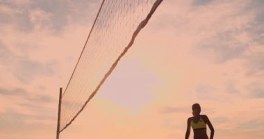 Plaj voleybolu maç kızlar kum üzerinde gün batımında yavaş çekimde topa vurdu.